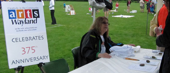 Margie at a desk with the sign 'Arts Wayland'