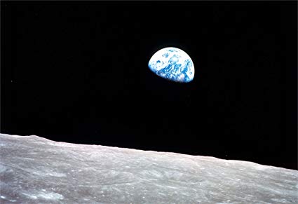 A half-lit earth hovering over the surface of the moon.